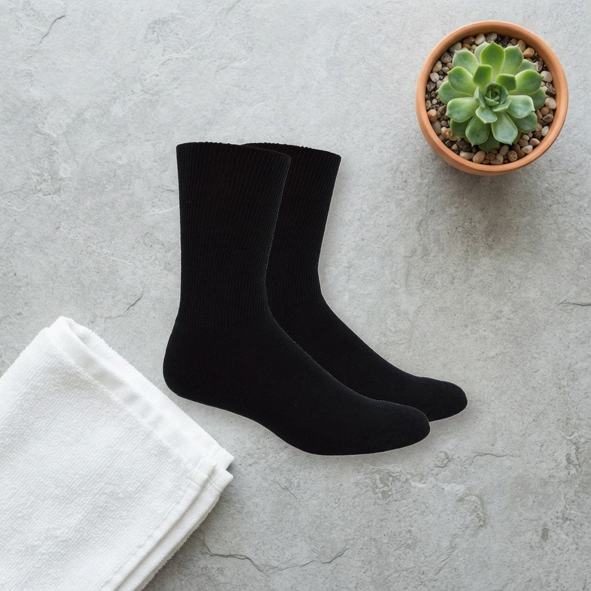 Mi Socks Black non-binding diabetic socks on a stone surface beside a folded towel